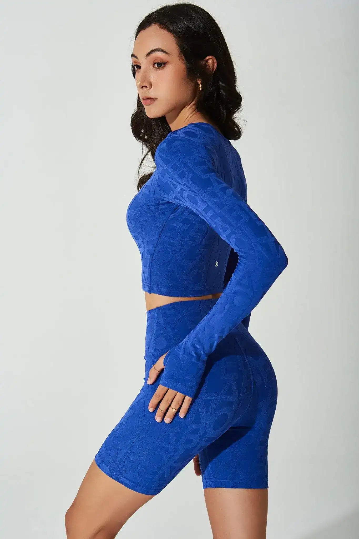 Woman in blue long sleeve crop top and matching high-waist biker shorts activewear set