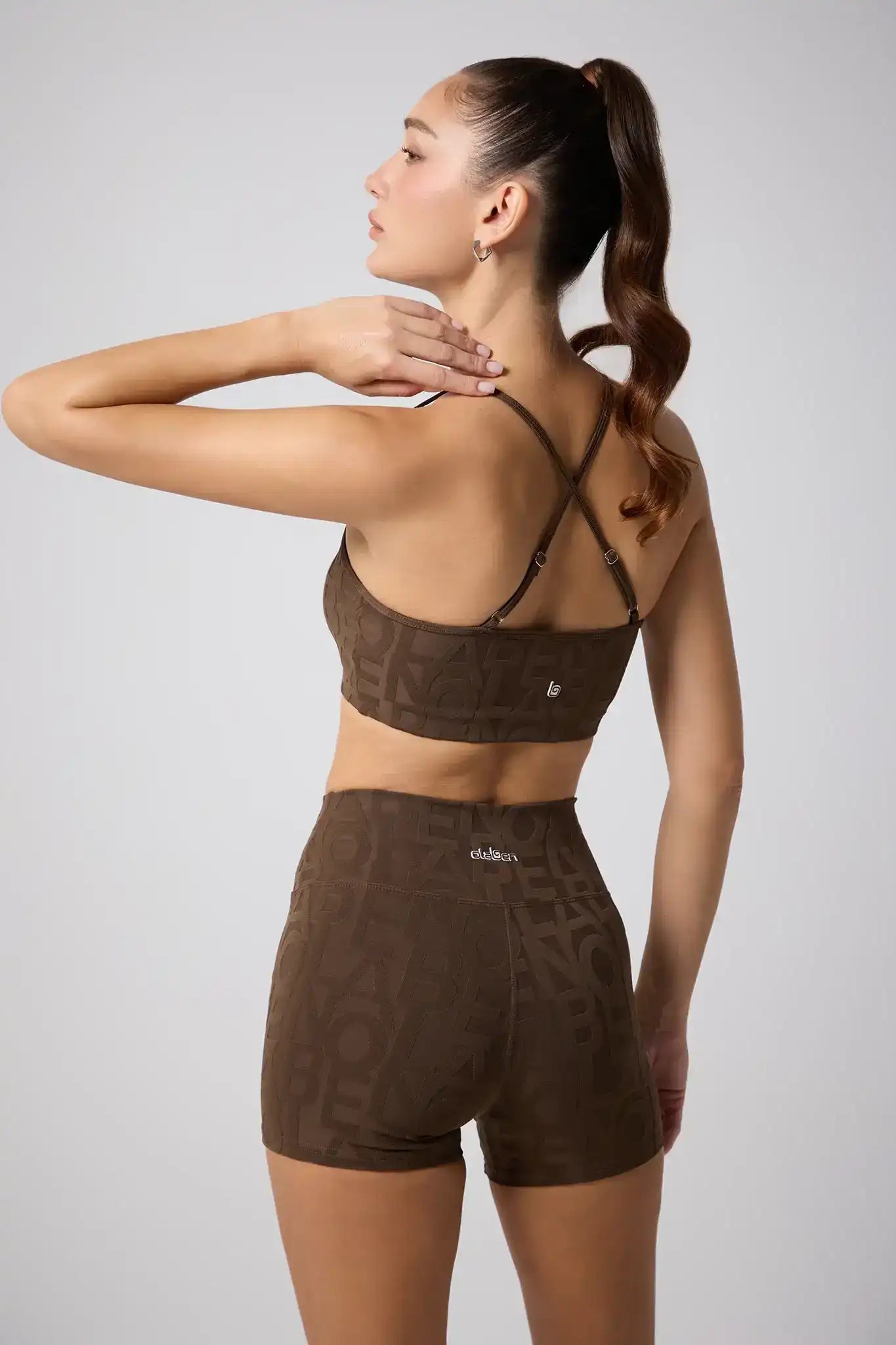 Woman in brown patterned sports bra and high-waisted shorts, back view, fitness activewear