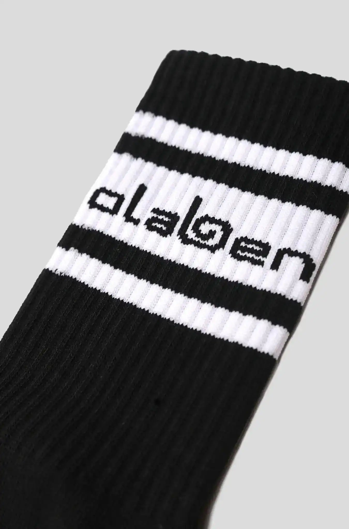 Black and white striped Olaben activewear sock with bold branding