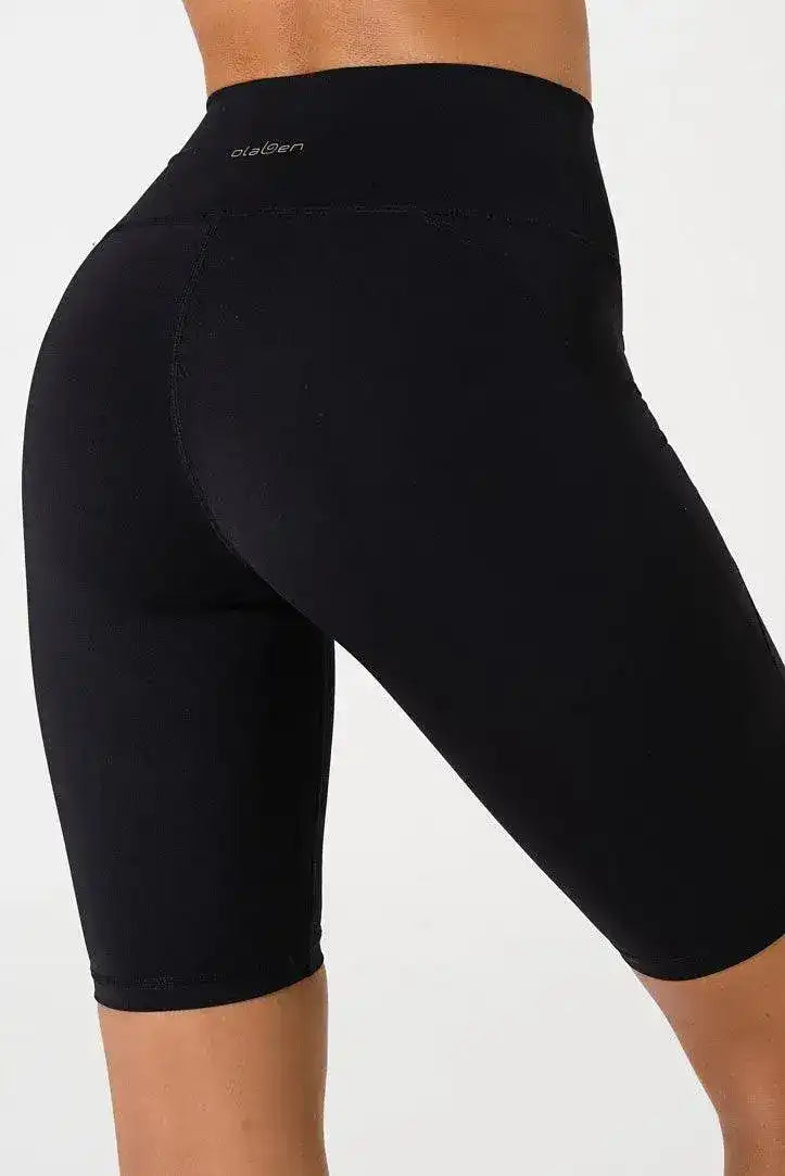 Close-up of woman wearing black high-waisted biker shorts, side view, on white background.