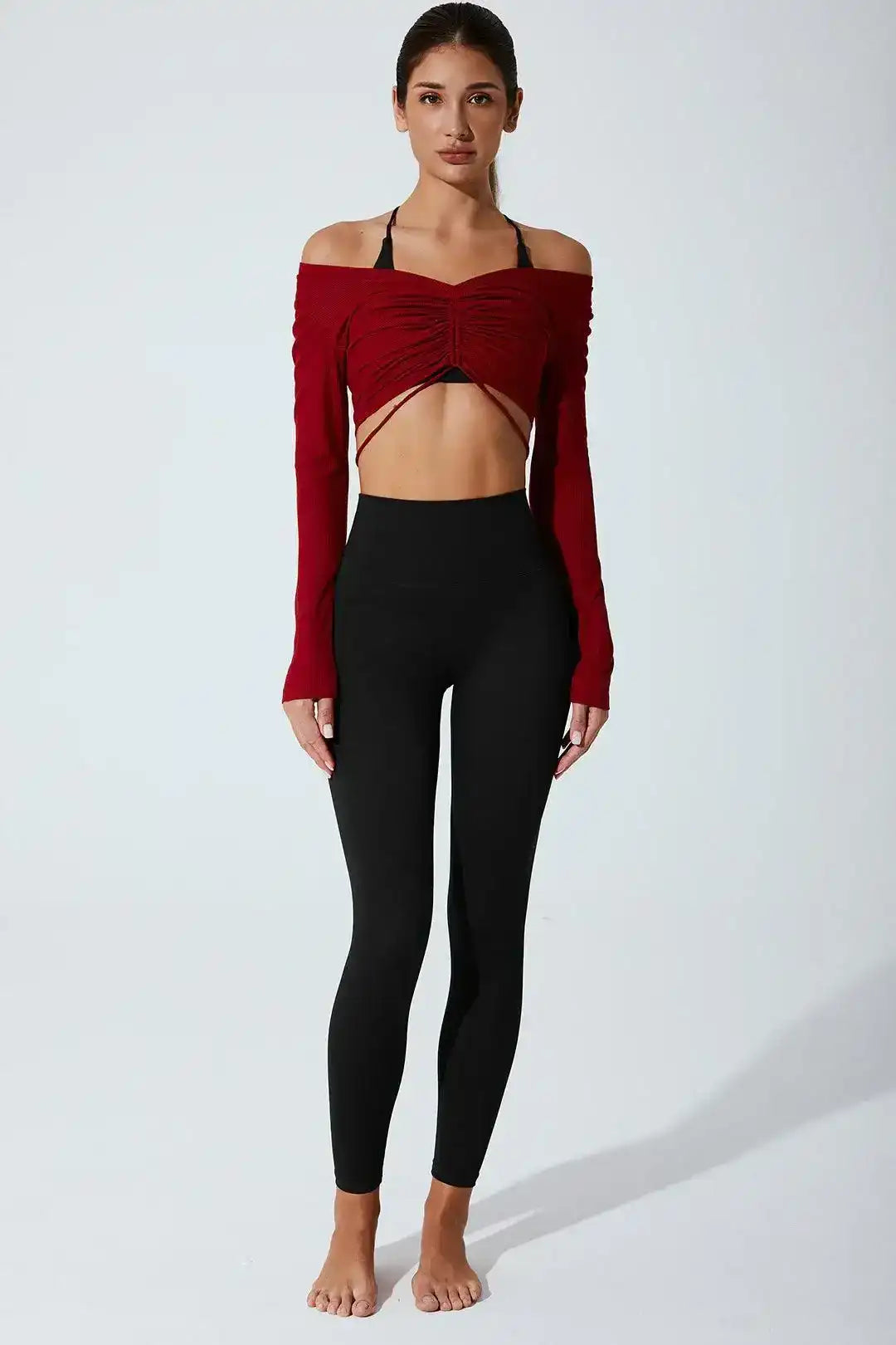 Woman wearing burgundy off-shoulder long sleeve crop top and high-waisted black leggings
