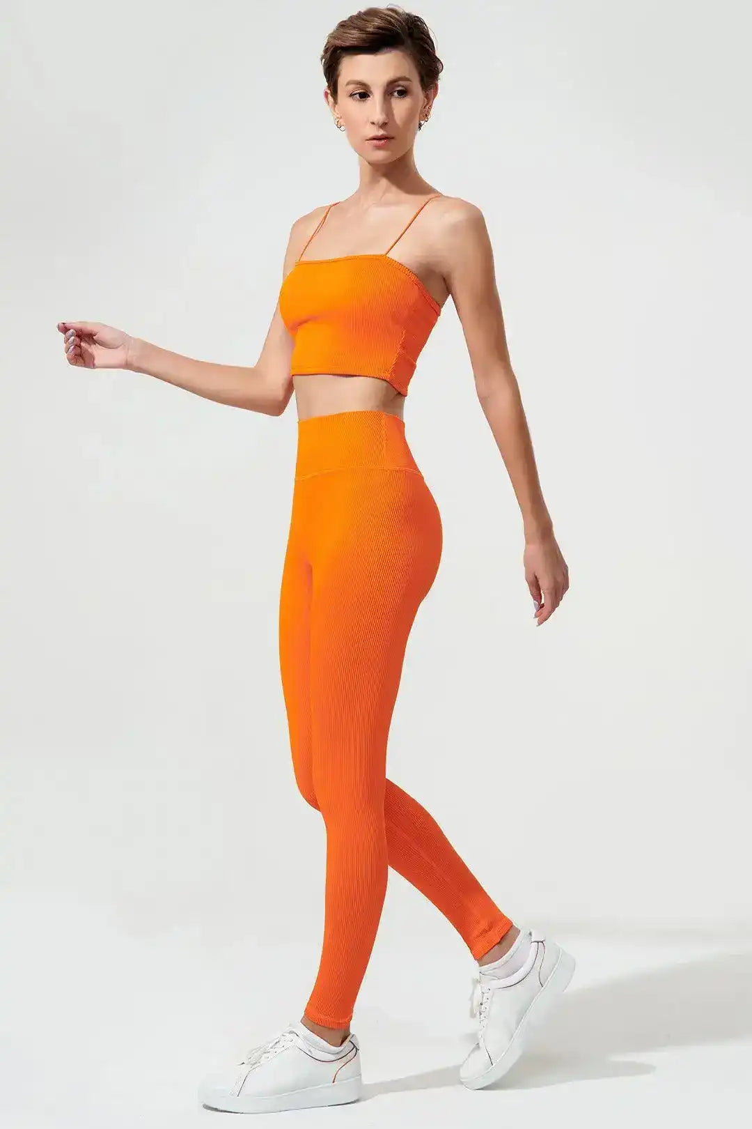 Woman wearing tangerine orange spaghetti strap sports bra and high-waisted leggings