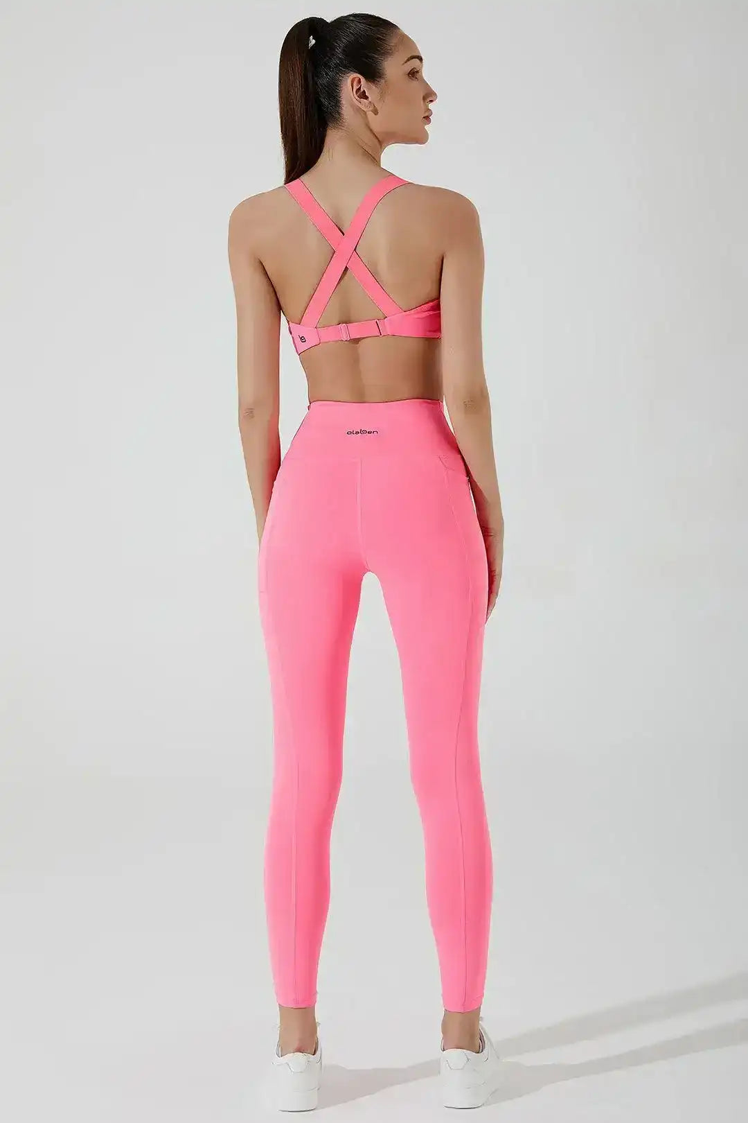 Woman wearing pink criss-cross back sports bra and matching high-waisted leggings