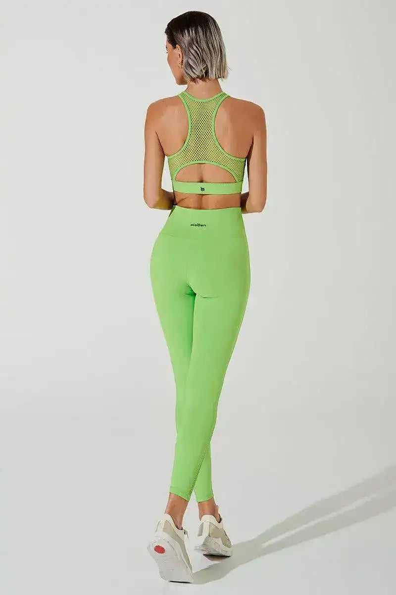 Woman in fluorescent green mesh leggings and matching sports bra, back view, studio lighting