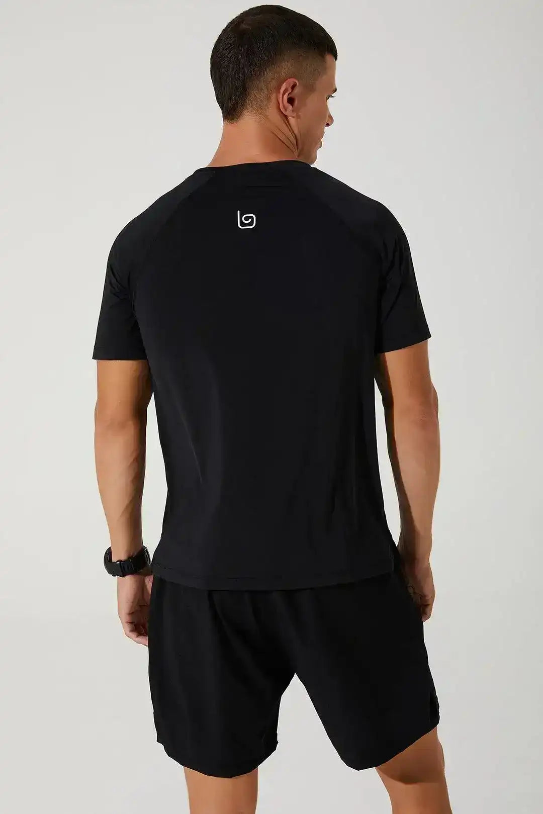 Back view of man wearing black crew neck athletic t-shirt and shorts