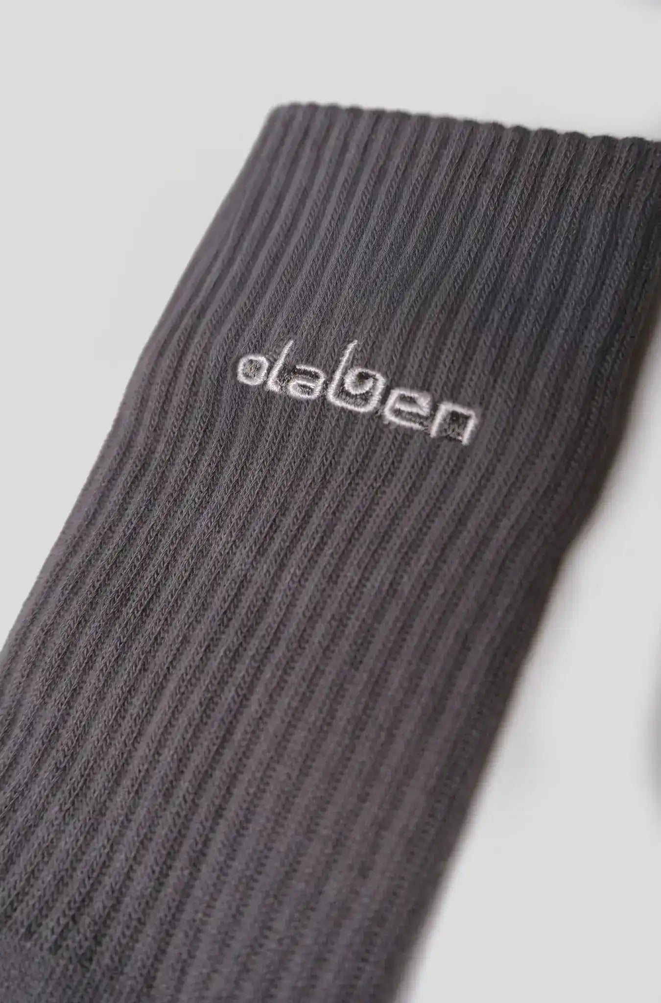 Gray ribbed activewear sock with embroidered Olaben logo, ideal for yoga and fitness