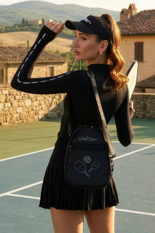 Woman in black activewear with branded visor and pickleball bag on tennis court