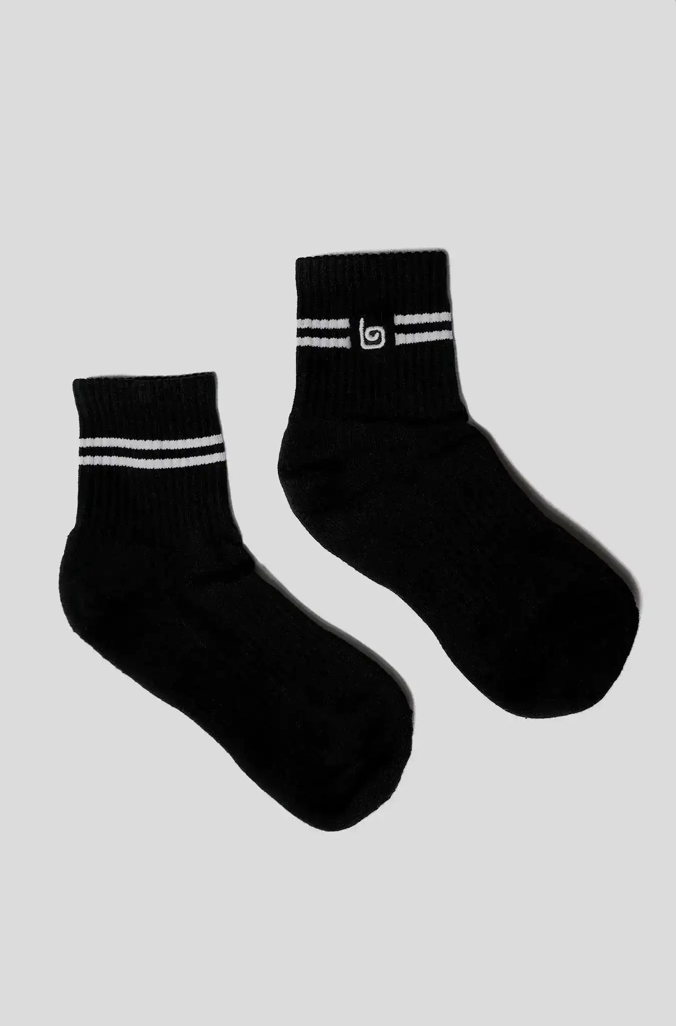 Black athletic socks with white stripes and logo, ideal for yoga and fitness activities.