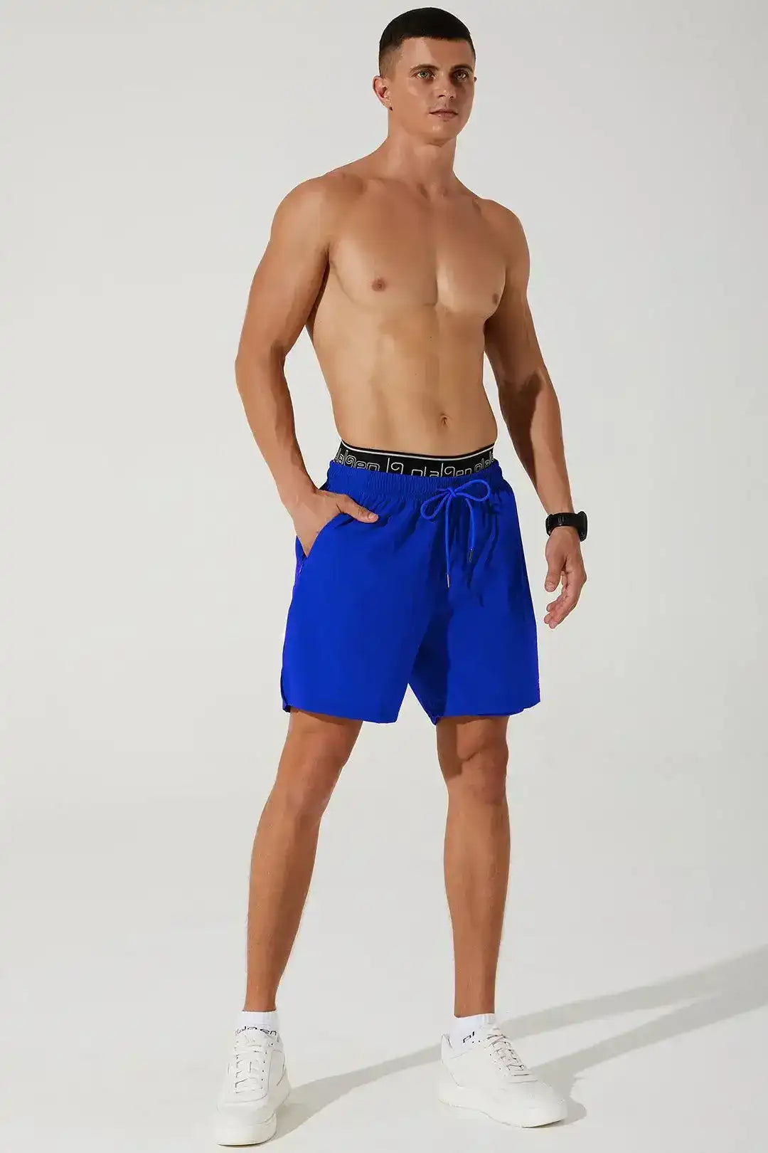 Athletic man in blue men's workout shorts with drawstring waistband and white sneakers