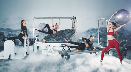 Women in activewear doing Pilates and stretching exercises with equipment in a modern, misty studio.