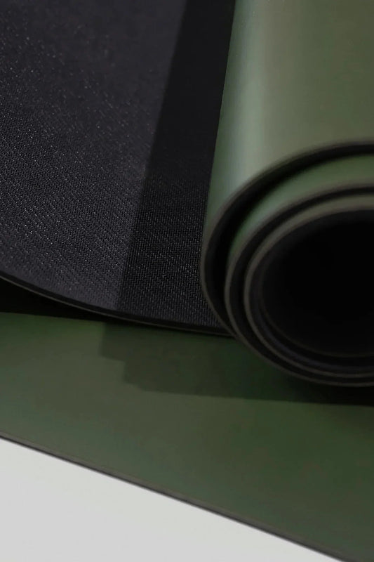 Close-up of rolled green and black yoga mat with textured surface for fitness and exercise