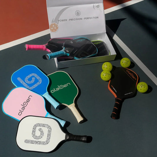 Colorful pickleball paddles and yellow balls on court with product packaging visible