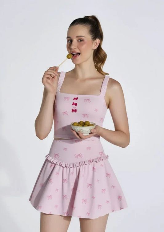 Woman in pink bow-patterned activewear skirt set eating grapes, holding a bowl