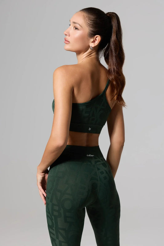 Woman wearing olive green one-shoulder sports bra and matching high-waisted leggings