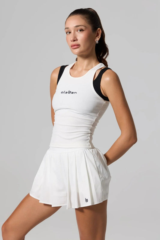 Woman wearing white double layer racer tank top and white pleated athletic skirt
