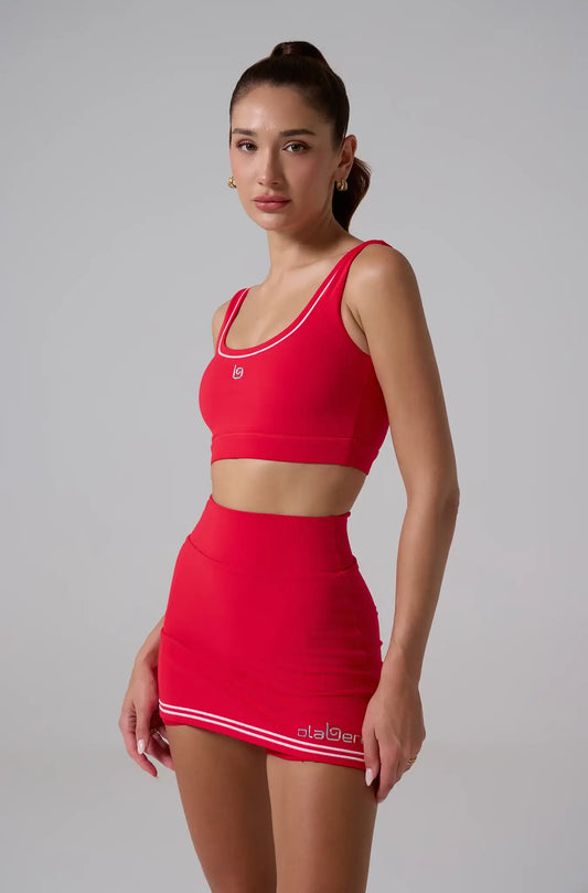 Woman wearing a lava red sports bra and matching high-waisted active skirt, stylish fitness outfit