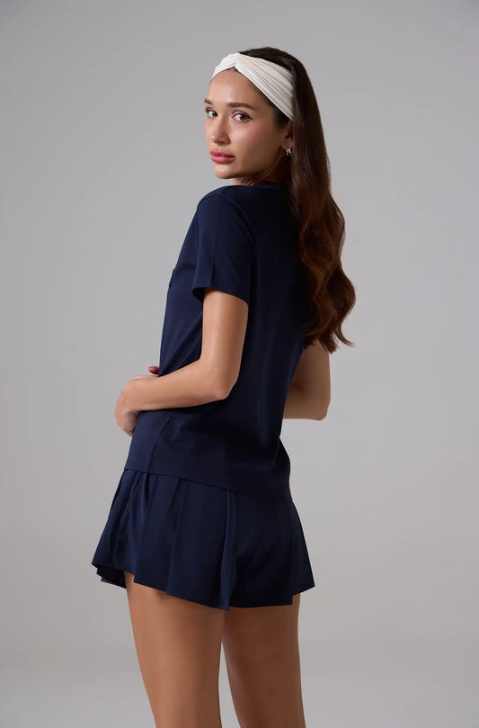 Woman in navy blue short sleeve activewear top and shorts with white headband, side view
