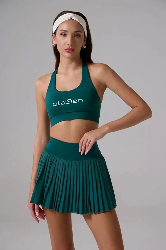 Woman wearing a green sports bra and pleated mini skirt, headband, fitness apparel