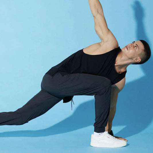 Man in athletic wear performing yoga pose on blue background