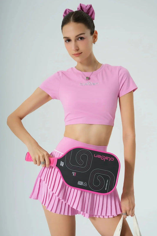 Woman in pink athletic outfit holding a pink pickleball paddle and wearing a hair bow