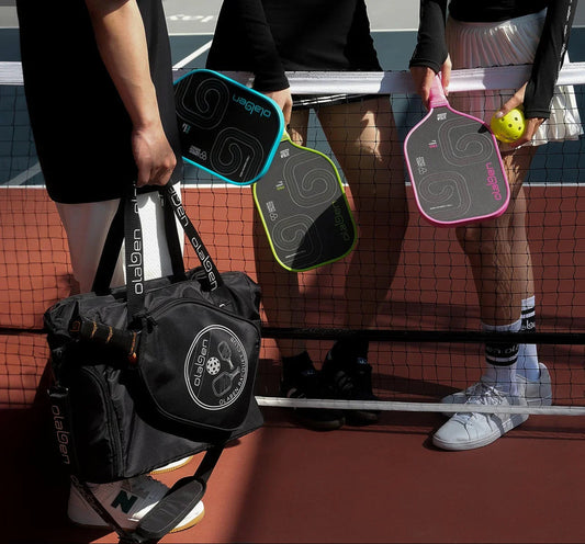 Players with pickleball paddles and bag on outdoor court, ready for pickleball game.
