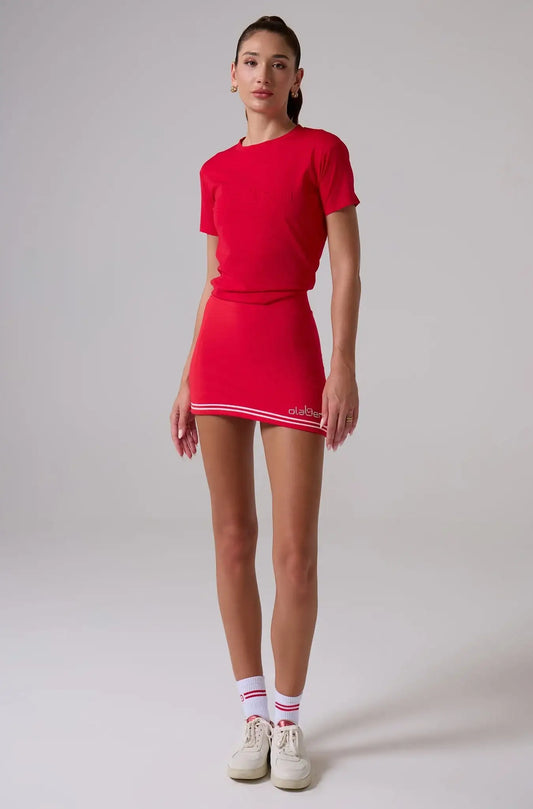 Woman wearing red athletic t-shirt, matching mini skirt with white trim, and striped crew socks