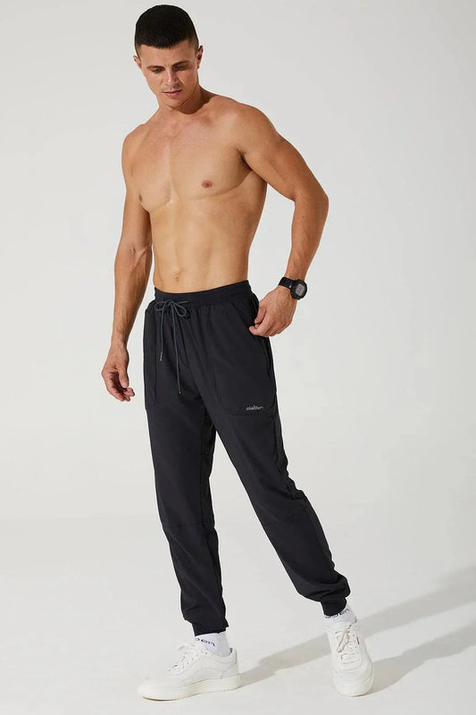 Athletic man modeling black men's jogger trousers with drawstring waist and side pockets