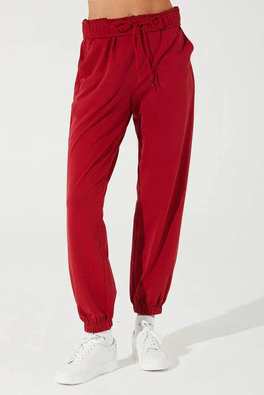 Woman wearing red sweatpants with elastic waist and cuffs, paired with white sneakers