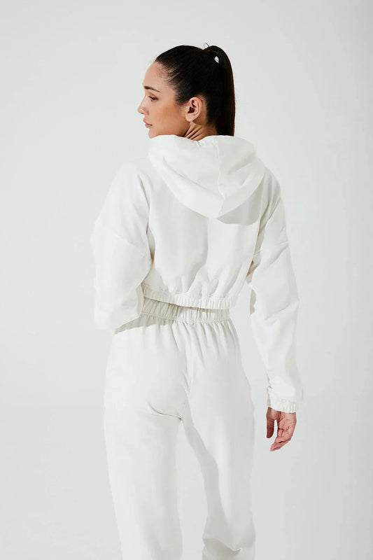 Woman wearing white cropped hoodie and white sweatpants, shown from the back