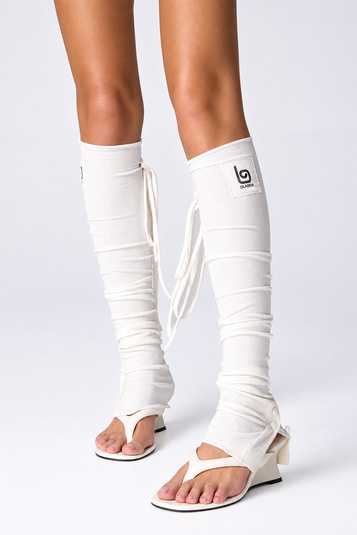 Olaben Barre Ruched Leg Warmers in White, front view with sandals