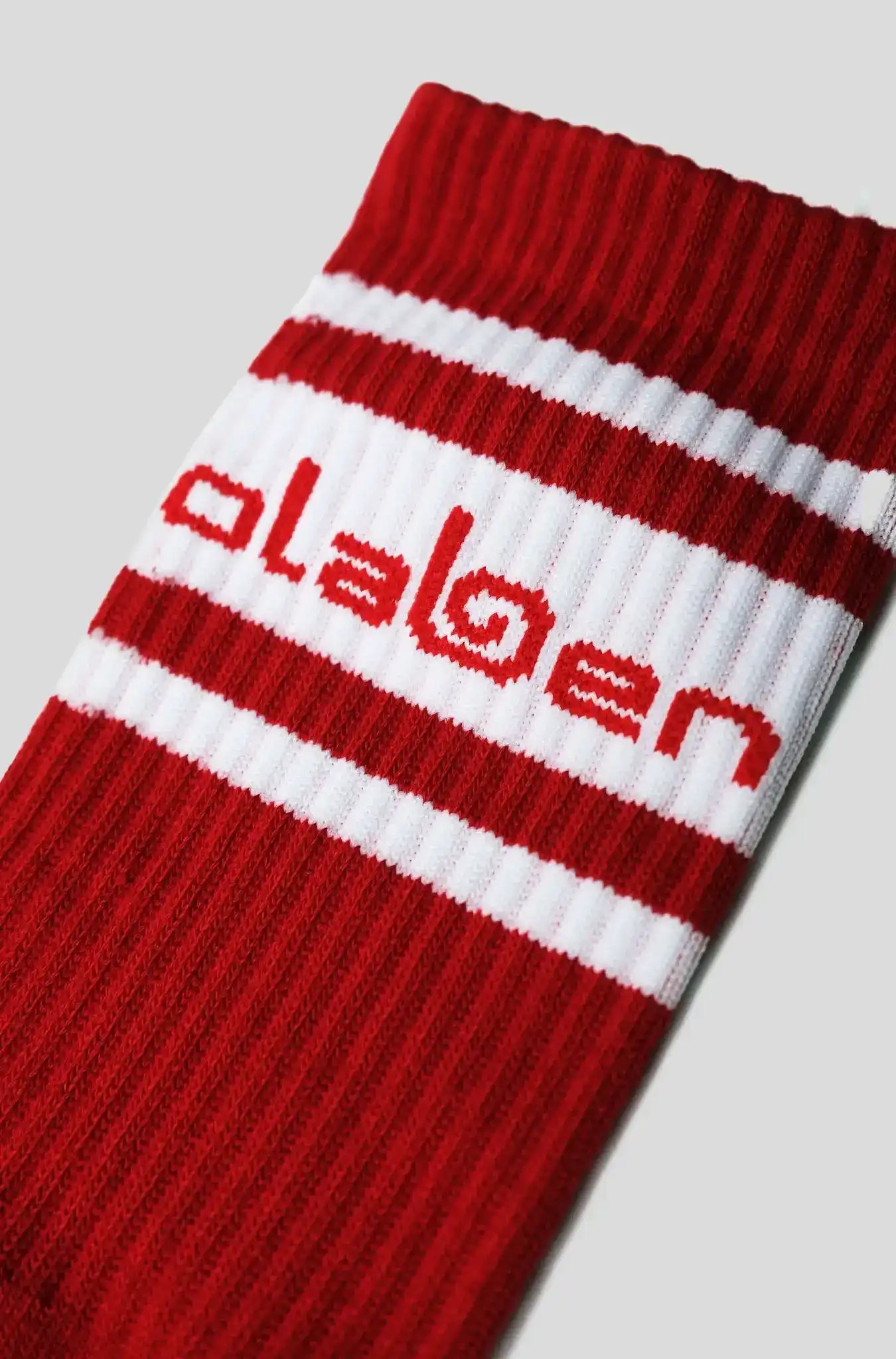 Red and white striped athletic sock with Olaben logo, ideal for fitness and active lifestyle