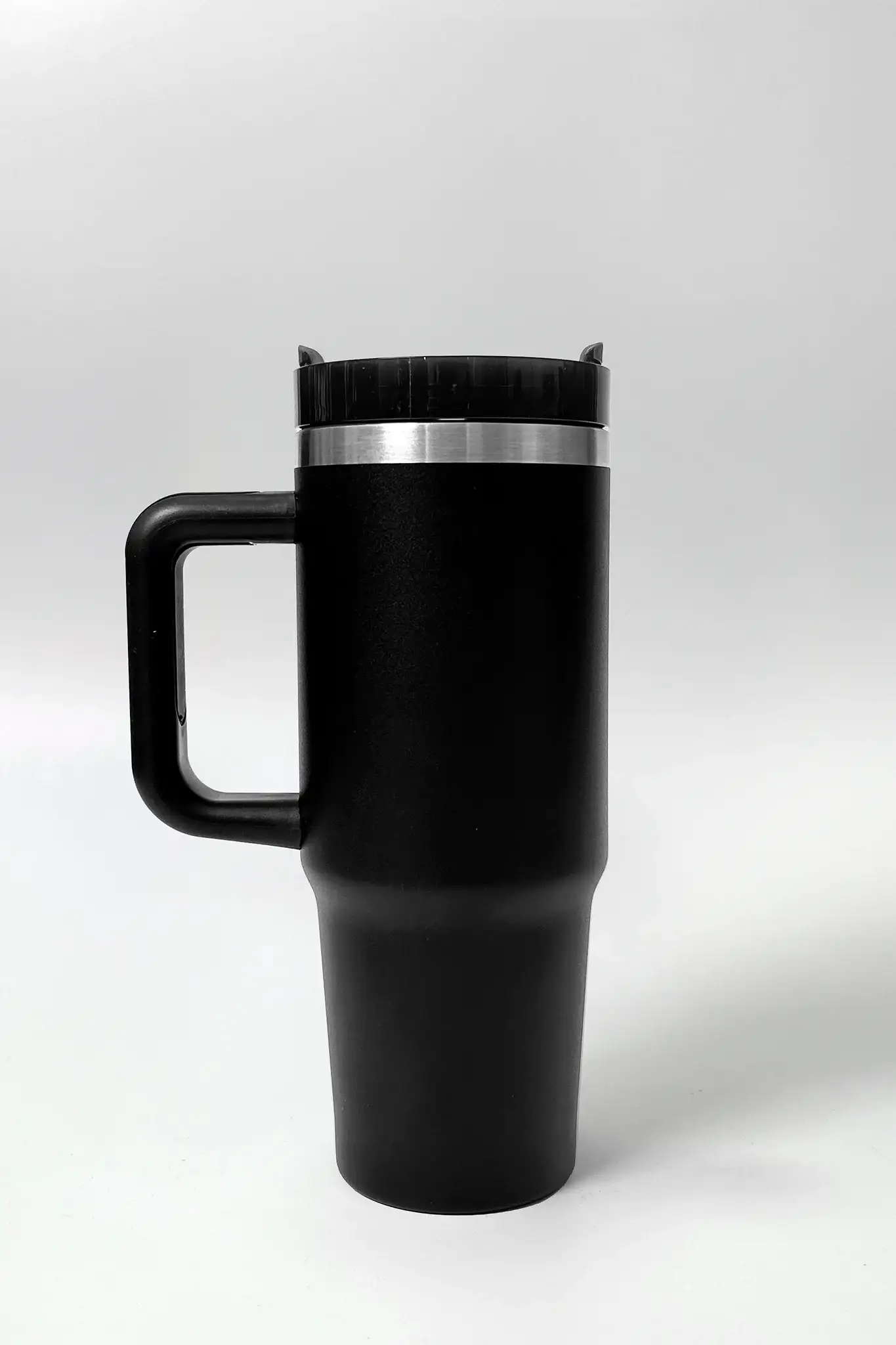 Black travel mug with handle and lid, ideal for on-the-go coffee or tea during workouts or daily commutes.