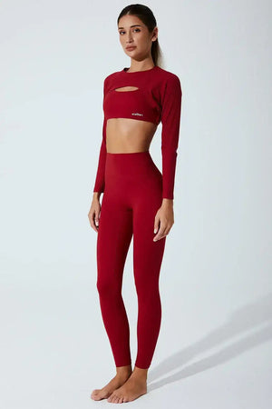 Woman wearing seamless red burgundy long sleeve sports bra and high-waist leggings set